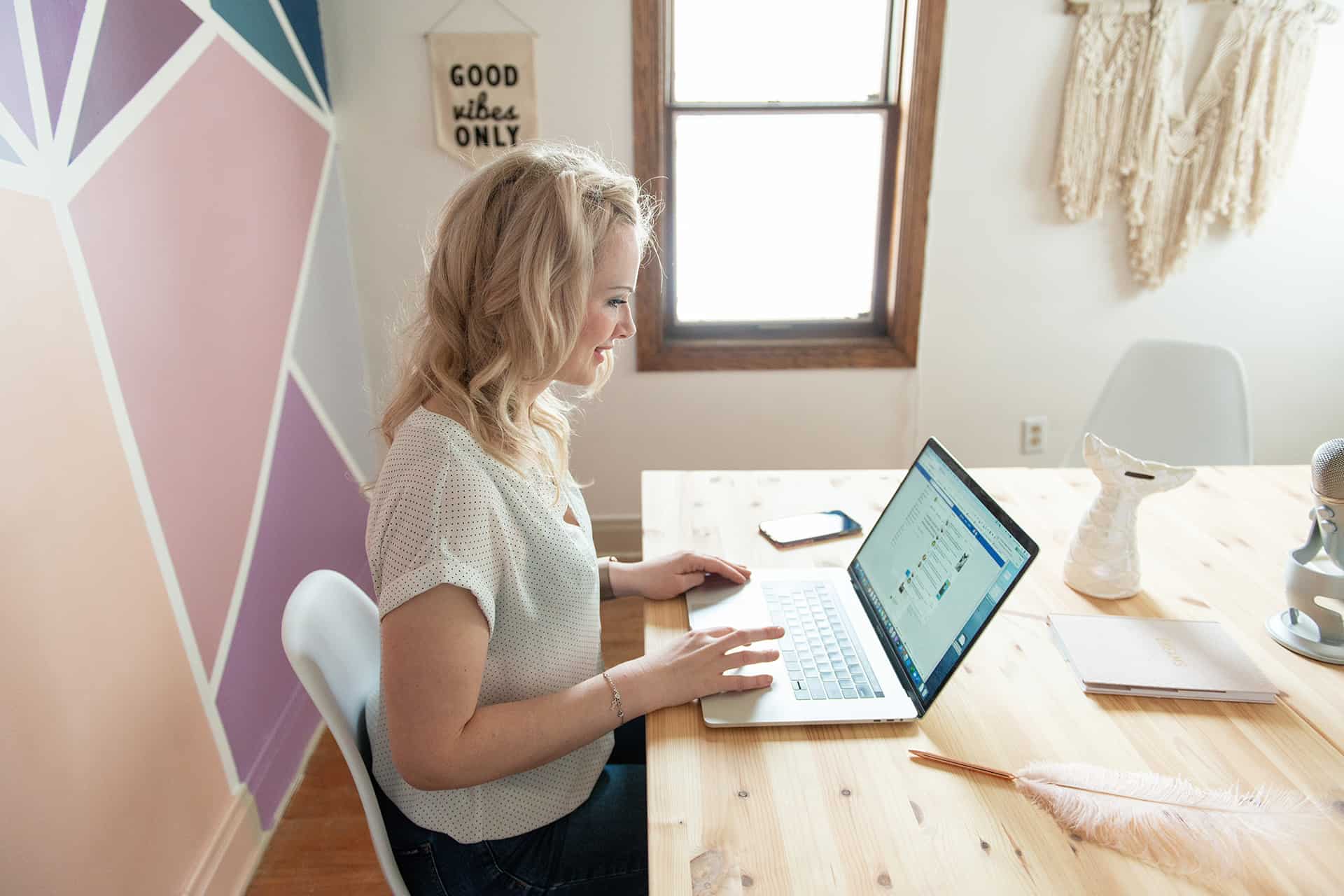 Sarah sitting at a desk with hands on a laptop