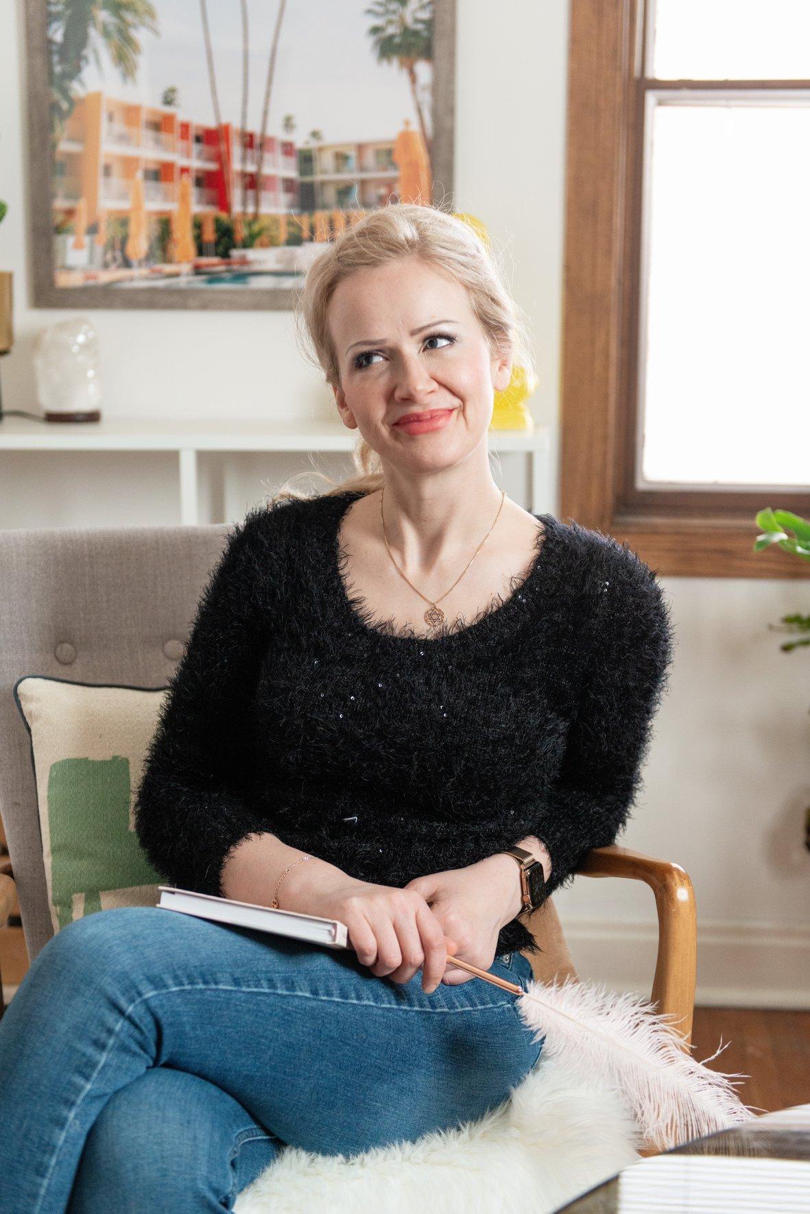 sarah sitting on top of a desk smiling at the camera